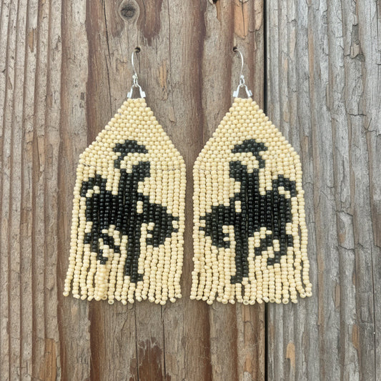 A pair of beaded fringe earrings depicting a black and cream cowboy on horse design, displayed against a white background with 'Badlands Beadwork' written at the top.
